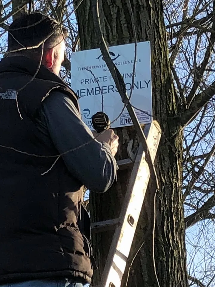 A member putting up a club members-only sign on a tree